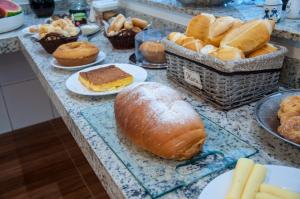 una mesa cubierta con pan y bollería en los platos en Hotel Pousada Beija Flor en Poços de Caldas