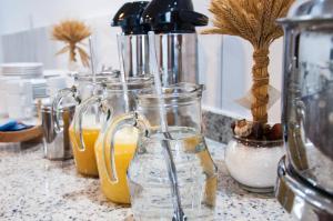 a counter with several glass jars of orange juice at Hotel Pousada Bortolan in Poços de Caldas