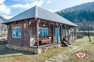 a small wooden cabin in a field with mountains at Gospodaria Lui Nea Ion in Vama Buzăului