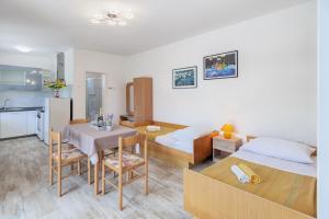 1 dormitorio con 2 camas, mesa y cocina en Apartment Ema, en Premantura