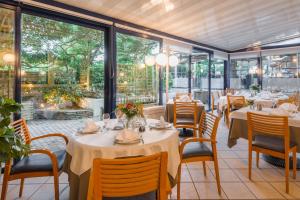 un restaurante con mesas, sillas y ventanas grandes en Logis Hotel Le Sablier du Temps, en Argentat