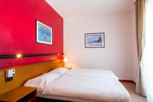 ein Schlafzimmer mit einer roten Wand und einem weißen Bett in der Unterkunft Hotel Pace in Torri del Benaco