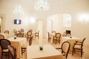 una sala da pranzo con tavoli, sedie e lampadari a braccio di ViverE' Resort a Presicce