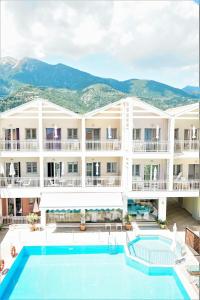 a hotel with a pool and mountains in the background at Aggelos Apartments & Deluxe Studios in Nydri