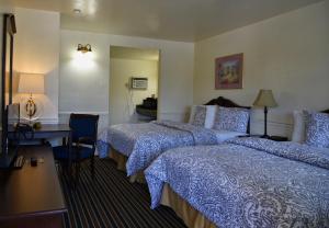 a hotel room with two beds and a desk at Monterey Pines Inn in Monterey
