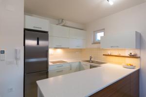 a kitchen with white cabinets and a stainless steel refrigerator at OrkulaBliss Apartments in Pašman +24 photos