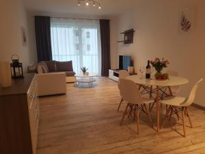 ein Wohnzimmer mit einem Tisch, Stühlen und einem Sofa in der Unterkunft Caskada Modern Apartments 2 in Słupsk