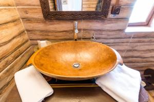 lavabo de madera en el baño con espejo en Gospodaria Lui Nea Ion en Vama Buzăului