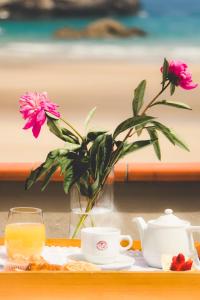 einen Tisch mit einer Vase Blumen und einer Vase Orangensaft in der Unterkunft Hotel Mirador de La Franca in La Franca