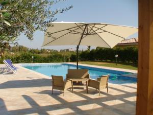 a table and chairs with an umbrella next to a pool at Hotel Villa Aurora in Latina