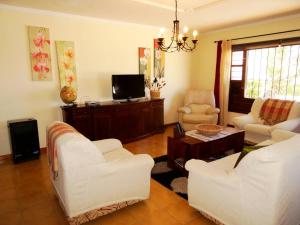 a living room with two white chairs and a tv at Casita Joli in La Asomada