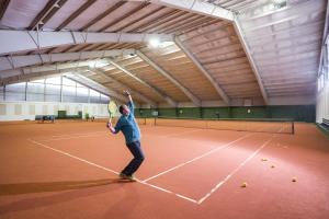 a man holding a tennis racket on a tennis court at Vital & Sporthotel Brixen in Brixen im Thale