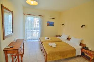 una camera d'albergo con due letti, una scrivania e una finestra di Falassarna Hotel a Chania