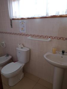 a bathroom with a toilet and a sink and a window at Prothea Home in Vila Chã