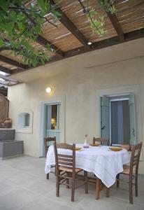 uma mesa de jantar com uma toalha de mesa branca e cadeiras em Mandarini House em Khokhlakiaí