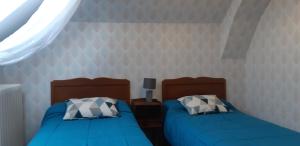two beds in a bedroom with blue sheets and a window at Logis hôtel LE COR D'ARGENT in Argent-sur-Sauldre