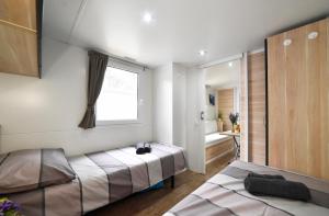 a bedroom with a bed and a window and a bathroom at Mobile Home MeeLi in Biograd na Moru