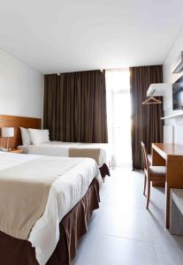 Pokój hotelowy z 2 łóżkami, stołem i biurkiem w obiekcie Herradura Hotel Suites w mieście Neuquén
