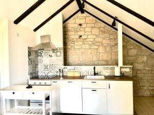 a kitchen with white cabinets and a stone wall at Familia in Selca +26 photos