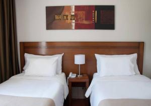 twee bedden in een hotelkamer met een telefoon ertussen bij Herradura Hotel Suites in Neuquén