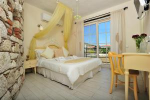 Alaçatı Sultan Konak Butik Otel ℳℛ Luxury Concept في ألاتشاتي: غرفة نوم بسرير ومكتب ونافذة