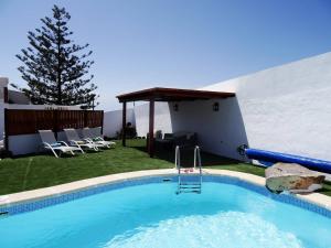 a large swimming pool with chairs and a gazebo at Casita Joli in La Asomada