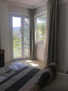 a bedroom with a bed and two large windows at La Moda Beach Hotel in Kaş