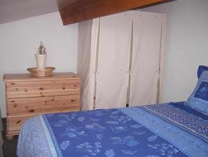 1 dormitorio con cama azul y tocador de madera en Mazet de vacances dans le Domaine de l'Espaï, en Saint-Martin-de-Brômes