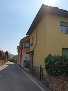 a yellow house with a fence next to a street at Casa Lavanda in Torri del Benaco