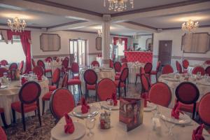 - une salle à manger avec des tables, des chaises et des archets rouges dans l'établissement Equinoxe Royal Reghin, à Reghin