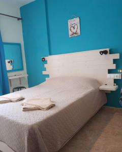 una camera con un letto bianco e una parete blu di Sokaki rooms a Città di Skiathos