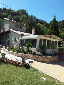 ein weißes Haus mit einer Veranda und einem Garten in der Unterkunft Gîte La Pequelette in Saint-Ambroix
