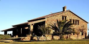 a stone house with a palm tree in front of it at Casa Rural Yeguada Jimenez Latorre in Fernancaballero