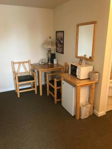 a room with a microwave and a table with a chair at Green Gables Inn in Cody