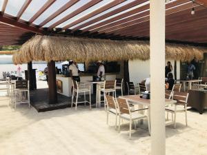 a restaurant with tables and chairs and a straw umbrella at CondoHotel 5th Avenue Std Double Studio in Playa del Carmen