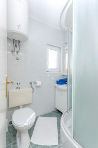 a white bathroom with a toilet and a sink at Apartments Vlasta in Tribunj