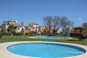 a swimming pool in a yard with houses in the background at (ROU002) Cómoda Casa con Puerta a la Piscina in Ayamonte