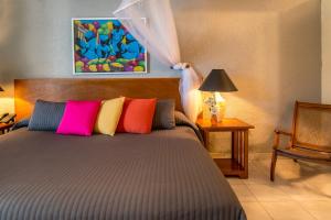 a bedroom with a bed with colorful pillows at Hotel Montana in Petionville