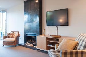 a living room with a tv and a fireplace at Sunrise Sanctuary in Wanaka