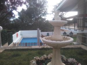 a stone fountain in a yard with a swimming pool at VILLA GARDEN in Tarragona