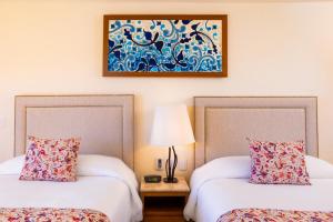 two beds in a room with a painting on the wall at Villa del Palmar Beach Resort & Spa in Cabo San Lucas
