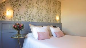 a bedroom with a bed with a vase of flowers on it at Hotel Garelos Betanzos in Betanzos