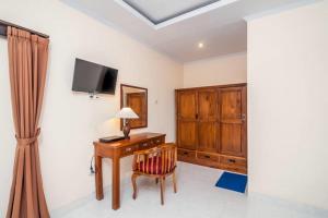 Habitación con escritorio y TV en la pared. en Private Villa Wayan, en Ubud