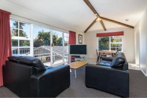 a living room with two leather chairs and a flat screen tv at Cherylea Motel in Blenheim