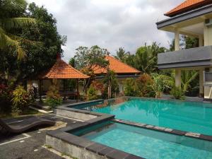 a swimming pool in front of a house at Agung Trisna Bungalows in Ubud