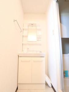 a white bathroom with a sink and a mirror at 湘南茅ヶ崎/湘南ライフの楽しめるアパートメント in Chigasaki