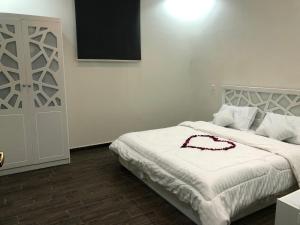 Un dormitorio con una cama blanca con un vestido rojo. en شاليه الماسة, en Taif