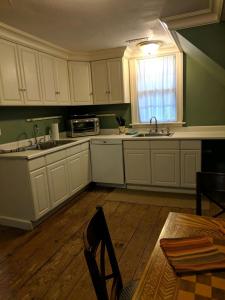 a kitchen with white cabinets and a sink and a window at Niagara Mansion Carriage Suite in Lewiston