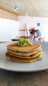 a stack of pancakes on a plate on a table at Akiri Surf Retreat in Thulusdhoo