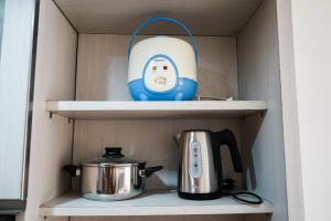 une théière et une bouilloire sur une étagère dans l'établissement Homey Studio Apartment at Margonda Residence 3 By Travelio, à Depok